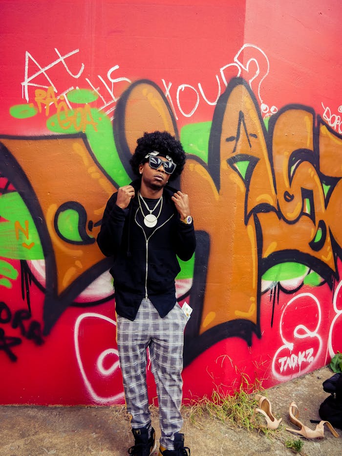 Fashionable man poses against vibrant graffiti wall showcasing urban street style.